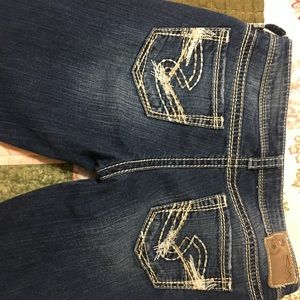 A pair of low rise boot cut silver jeans